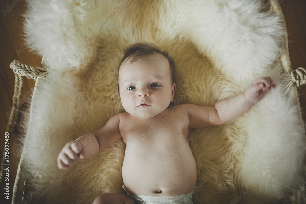 Cute, naked baby girl lying on sheepskin blanket in basket Cute, naked baby girl lying on sheepskin blanket in basket