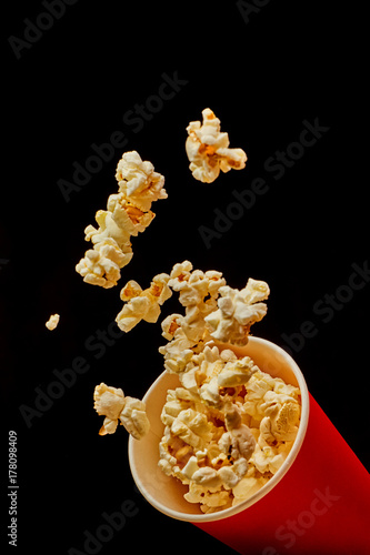 Popcorn flying out of the bucket on black background