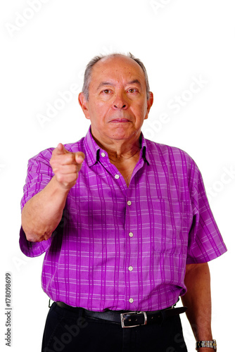 Portrait of a happy old man, pointing with his hand to somewhere wearing a purple square t-shirt in a white background