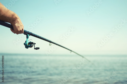 A fisherman holds a fishing rod, a close-up hand, an instagram