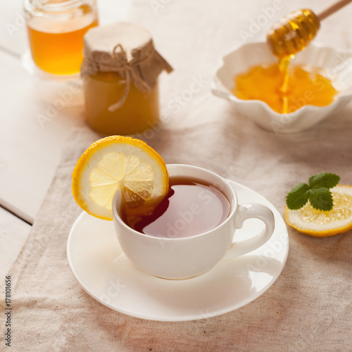 Cup of herbal tea, honey and lemon on wooden background