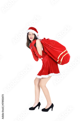 Christmas concept : Beautiful young Asian woman in Santa Claus clothes and hat carrying Santa big heavy bag over shoulder isolated on white background
