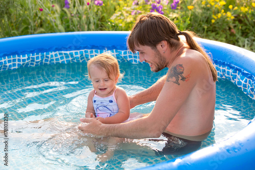 Dad and daughter in the paddling pool outdoors © guardalex