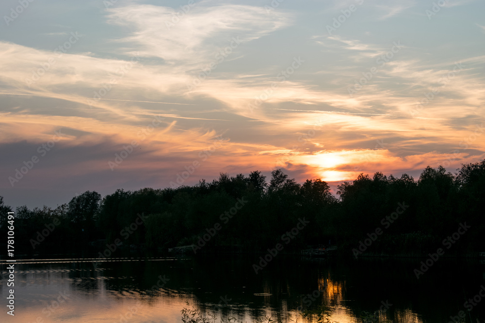 Beautiful panoramic Sunset by the forest across the lake	