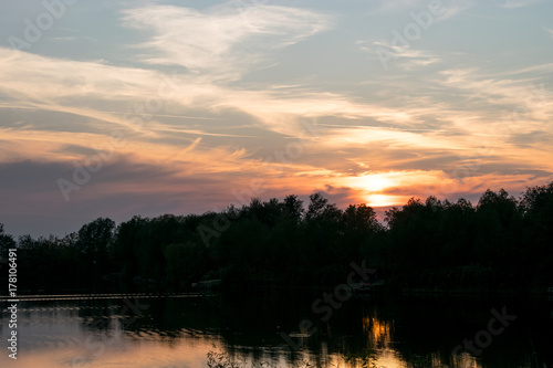 Beautiful panoramic Sunset by the forest across the lake 