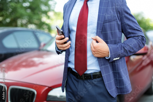 Handsome successful businessman near car outdoors