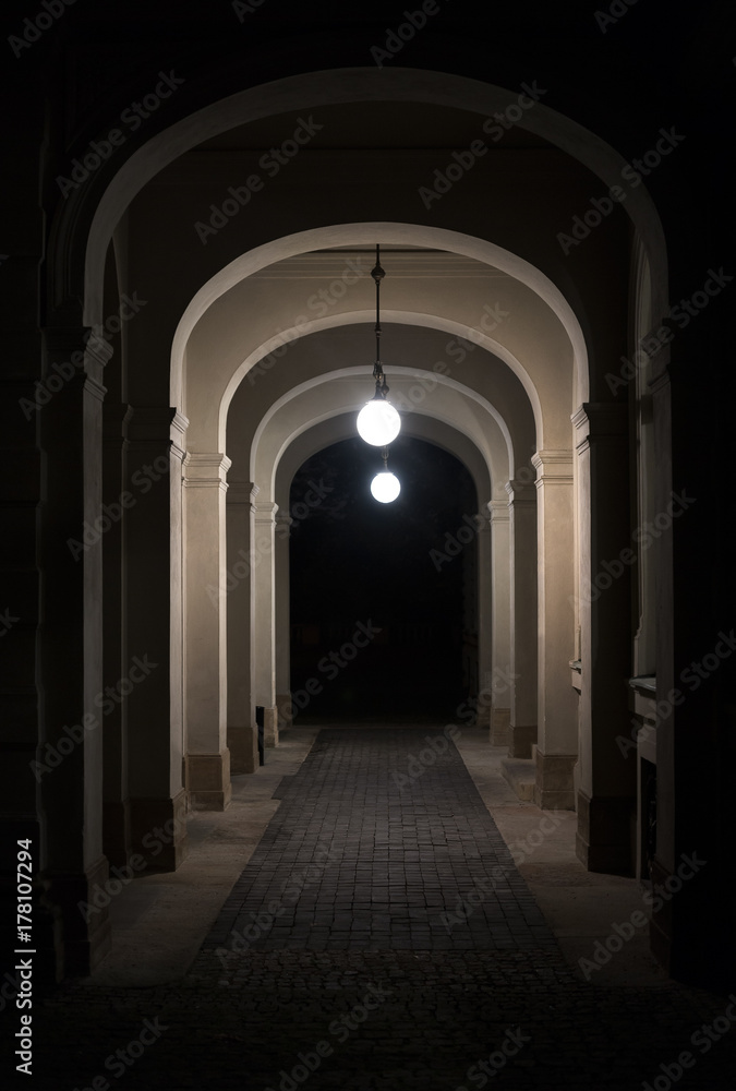 Narrow alley during night. Passage is lit by light. Lantern is on the top. Beginning and ending corridor is in the dark Narrow alley during night. Passage is lit by light. Lantern is on the top. Beginning and ending corridor is in the dark