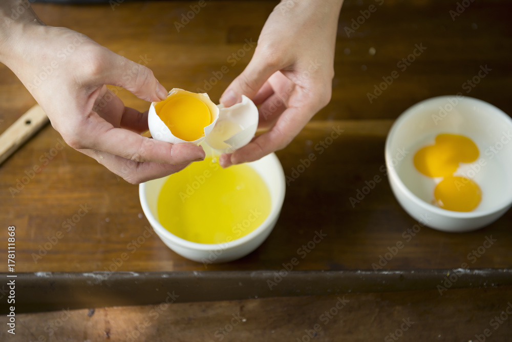 Foto de Woman hands separating egg yolk for brushing bread do Stock