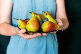 Close up woman holds plate with plums and pears