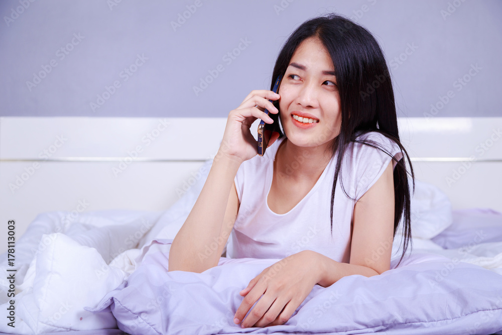 woman talking on cellphone on bed in bedroom woman talking on cellphone on bed in bedroom