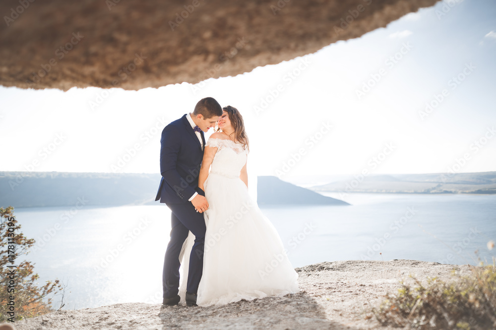Elegant stylish happy wedding couple, bride, gorgeous groom on the background of sea and sky Elegant stylish happy wedding couple, bride, gorgeous groom on the background of sea and sky
