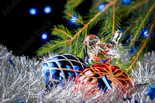Christmas decorations lying in tinsel and fir branches on a dark background with blurred lights