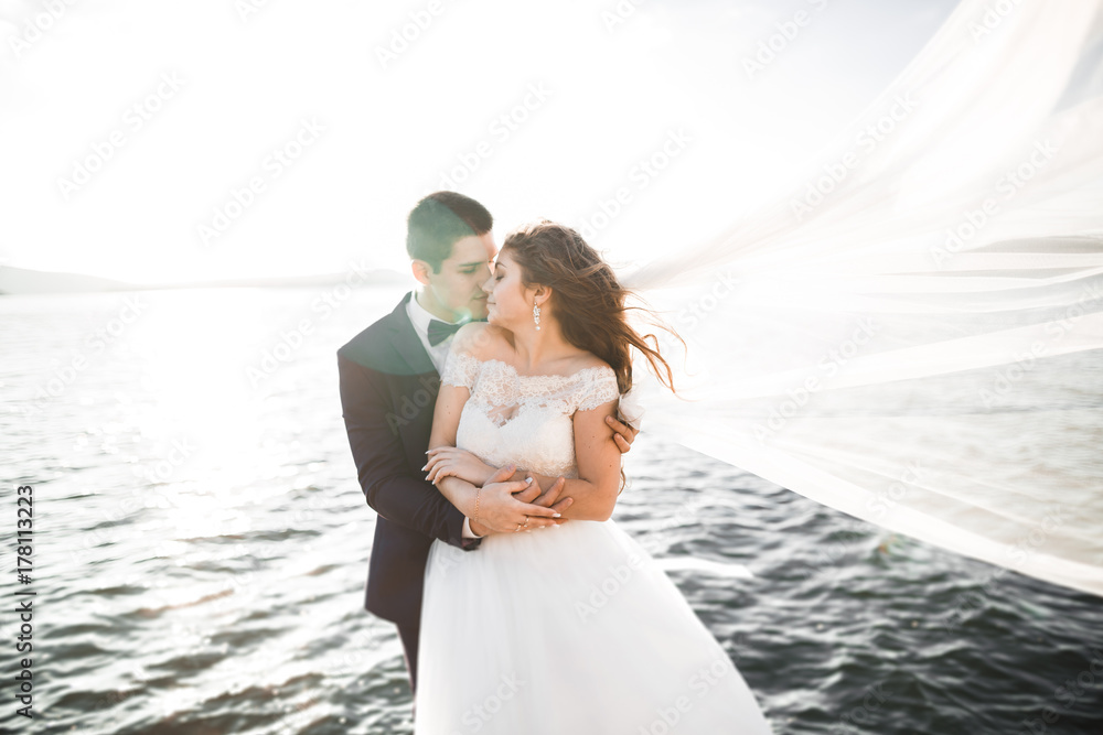 Happy and romantic scene of just married young wedding couple posing on beautiful beach Happy and romantic scene of just married young wedding couple posing on beautiful beach