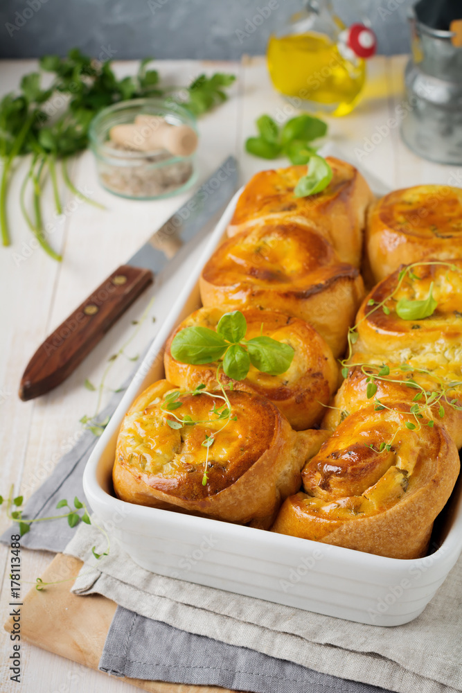 Buns with feta cheese and basil of yeast dough on a light wooden background. Selective focus. Rustic style. Buns with feta cheese and basil of yeast dough on a light wooden background. Selective focus. Rustic style.