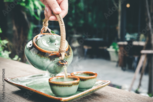 Bild auf Leinwand Hand pouring hot tea in the morning with fresh and happy, vintage tone