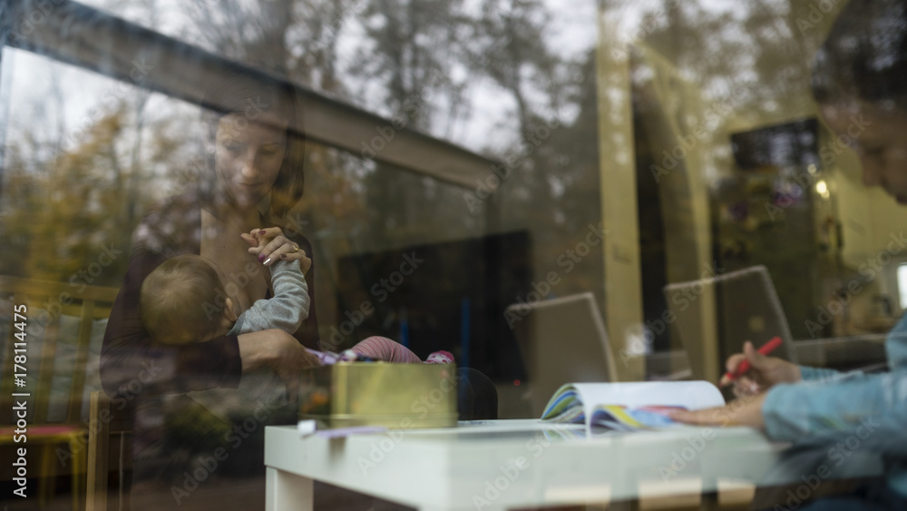 Obraz premium Young family inside the home through the window