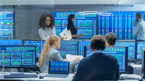 Multi-Ethnic Team of Traders is Busy Working at the Stock Exchange Office. Dealers and Brokers Buy and Sell Stocks on the Market. Monitors Display Relevant Infographics, Data and Numbers.