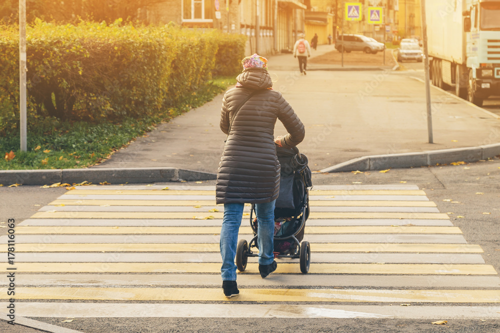 woman with a baby stroller at a pedestrian crossing