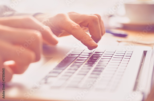 A closeup of an office worker using a computer keyboard, laptop on a sunny morning, evening.