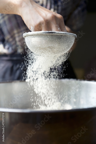 Young woman hands sifting flour for baking photo