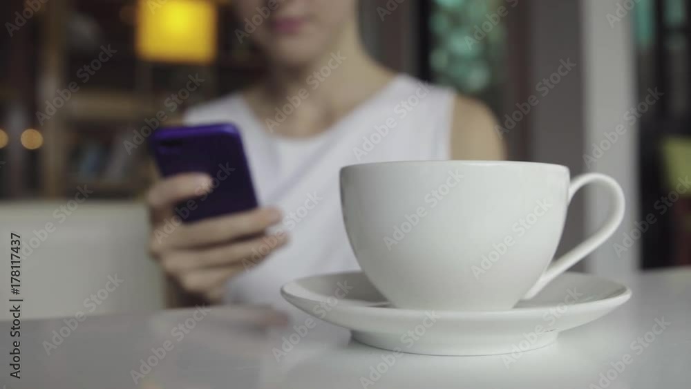 Female using smartphone while drinking coffee Female using smartphone while drinking coffee