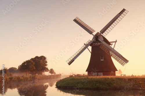 charming windmill by river at sunrise