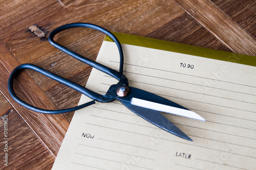 Vintage black scrissor with to do list over wooden background photo