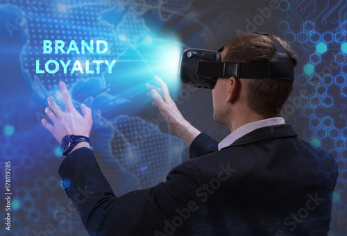 Business, Technology, Internet and network concept. Young businessman working in virtual reality glasses sees the inscription: Brand loyalty