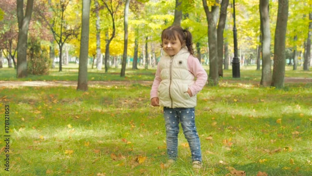 Happy child in autumn park. Little girl is playing with a ball in the park. Happy child in autumn park. Little girl is playing with a ball in the park.