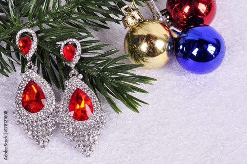 earrings with red stones on a branch of a Christmas tree with a ball
