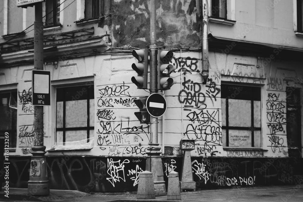 Fototapeta premium Ulica getta miasta namalowała graffiti i oznaczenia. Brudne rysunki na ścianach miasta. Fotografia artystyczna lub społeczna. Brudne ściany w napisie. Znak stop sygnalizacji świetlnej.