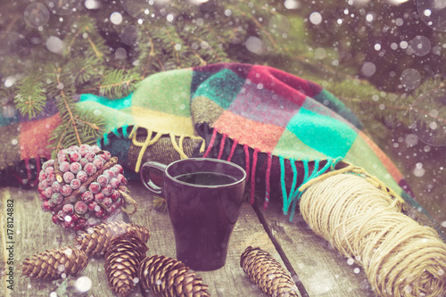 Cup of hot coffee on a rustic table. Winter still life of balls, cones, plaid, fir branches. Preparing for Christmas.