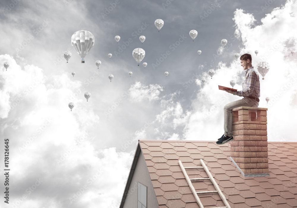 Handsome student guy reading book and aerostats flying in air Handsome student guy reading book and aerostats flying in air