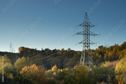 high voltage post at autumn forest. High-voltage tower sky background.