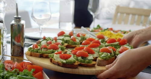 Waiter Serves Beautiful Organic Avocado Sandwiches/ Bruschetta on a Wooden Tray, Table Furnished in Mediterranean Food: Seasonal Vegetables, Olive Oil