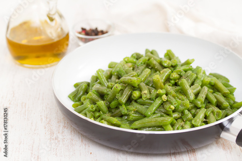 green beans on frying pan on wooden background