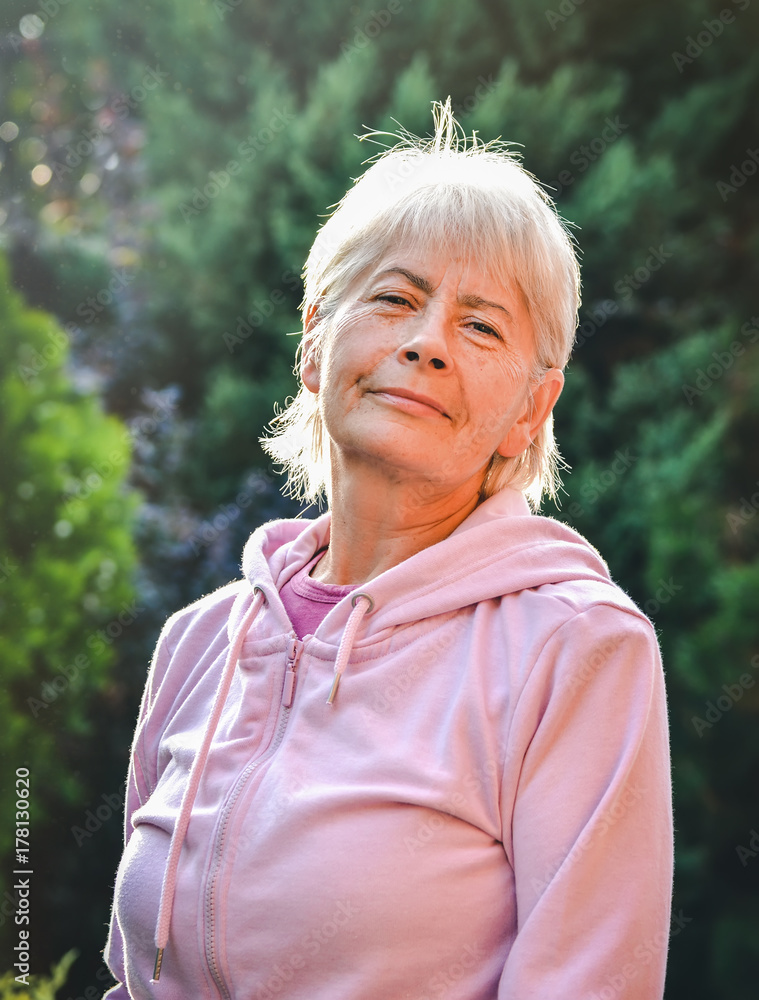 Old woman smiling outside during the sunny day. Laughing grey haired senior woman outdoors in a lush green park, close up portrait. Old woman smiling outside during the sunny day. Laughing grey haired senior woman outdoors in a lush green park, close up portrait.