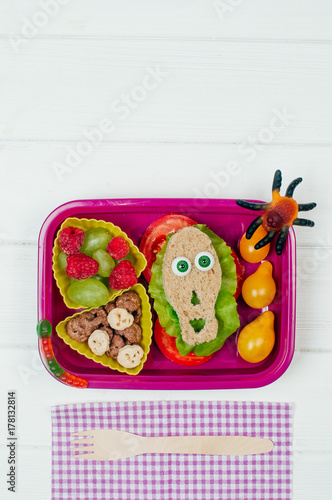 Halloween lunch box with school lunch on white wooden background