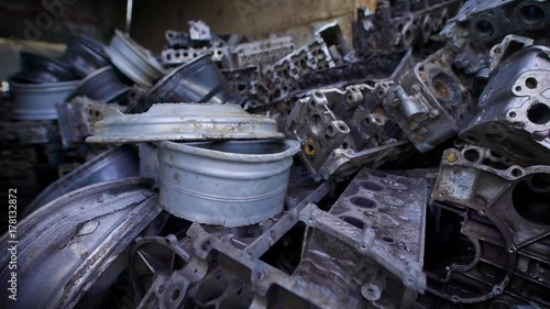 metal parts of old broken automobiles are lying in heaps of scrap metal in large hangar, old humps and engines photo