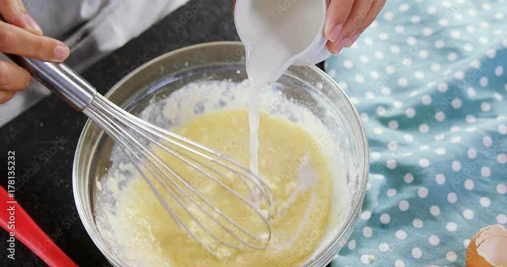 Woman adding milk to beaten eggs in a bowl Woman adding milk to beaten eggs in a bowl