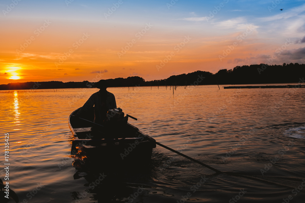 a man on long tail boat going into the sun set a man on long tail boat going into the sun set