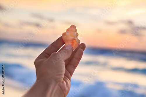 Woman Holding Small Shell in Her Hand at the Tropical Beach at Sunrise time