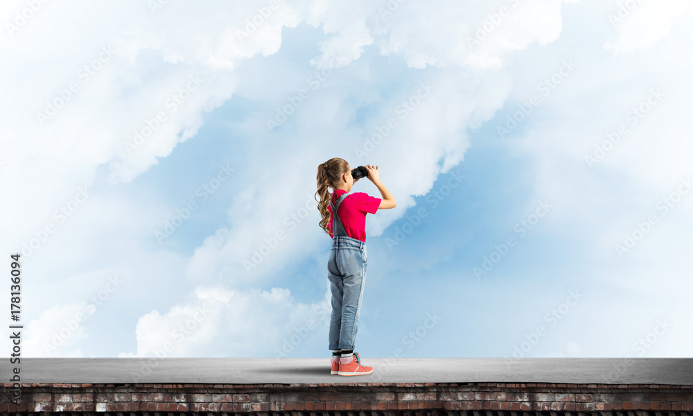 Obraz premium Concept of careless happy childhood with girl of school age looking in future