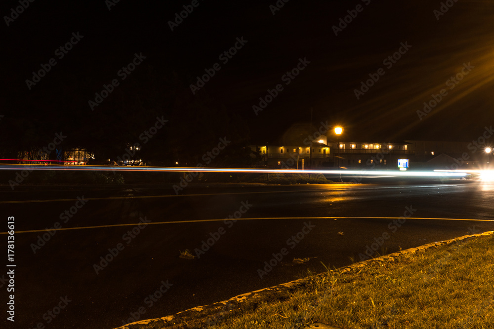 Long exposure light trail of night traffic on a quiet small town main street during a mist rain