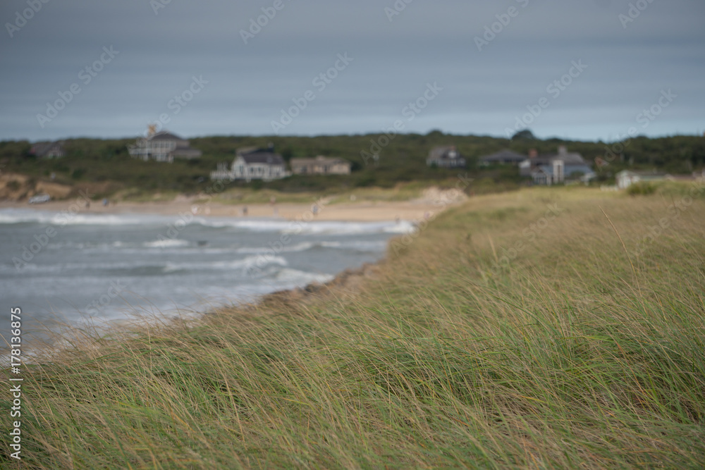 Coastline view overlooking sand dune grass towards expensive real estate summer homes on the ocean beach