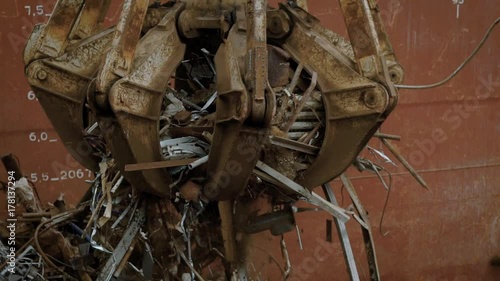 huge industrial grapple is moving captured scrap metal and throwing it down, for sorting in a big rubbish dump