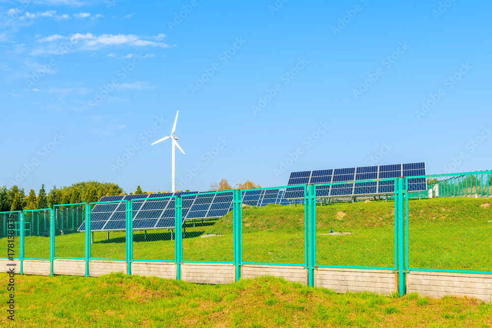 Solar panels on green field with wind turbine in background, Poland Solar panels on green field with wind turbine in background, Poland