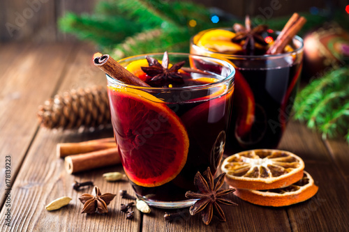 Two glasses of christmas mulled wine with oranges and spices on wooden background. photo