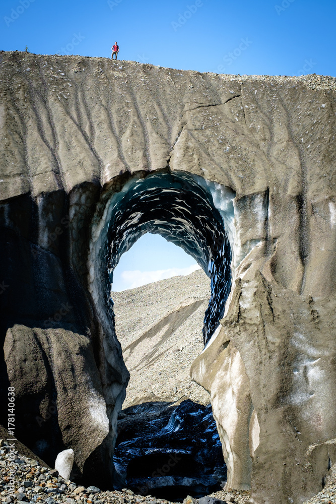 Fototapeta premium tall glacier arch with a man on the top