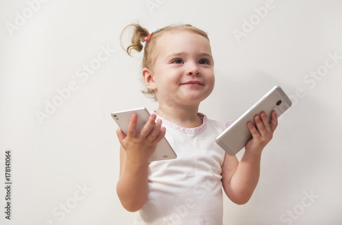 cute baby girl playing with two mobile phones on white